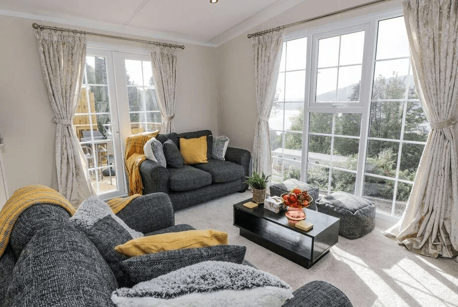 Living room at 11 Mansion View with large windows framing Loch Long from grey sofas with yellow cushions