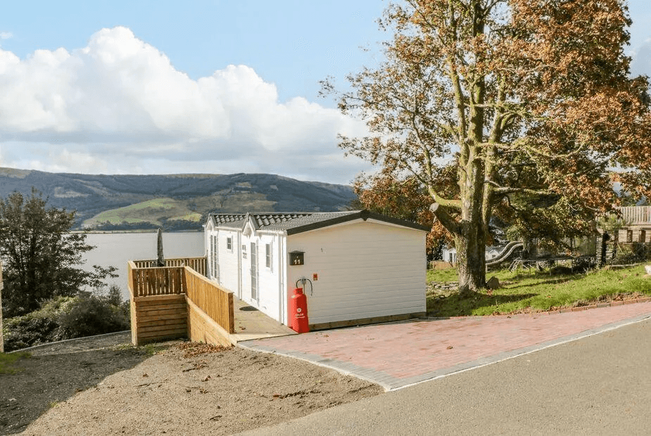11 Mansion View white-clad lodge with mature autumn tree and Loch Long behind