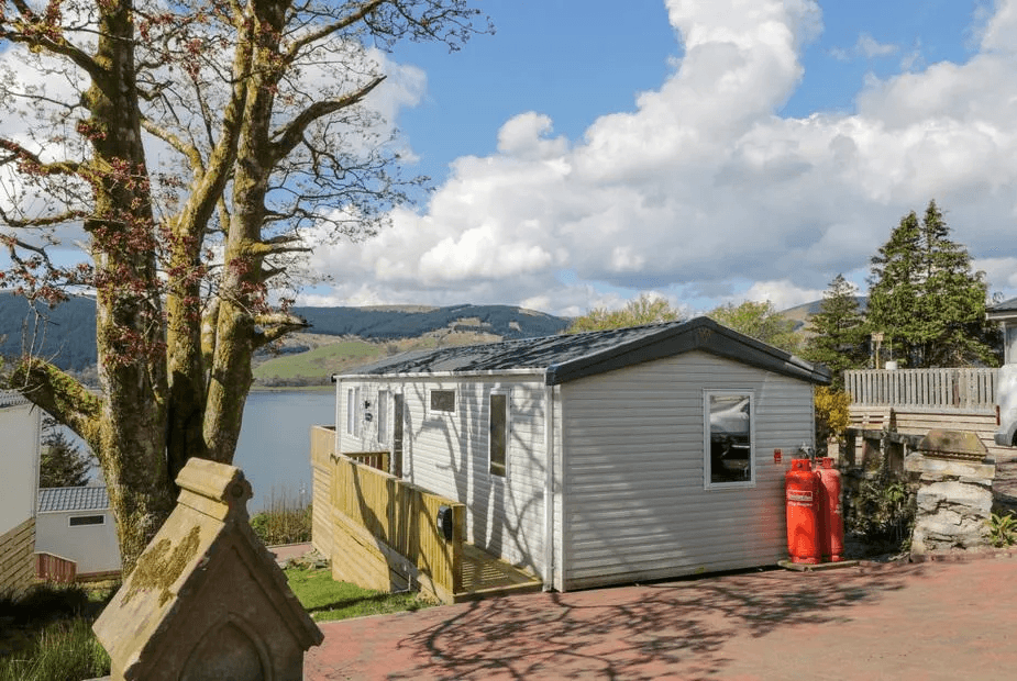 11A Mansion View white-clad lodge with mature trees and Loch Long in the background, Cove