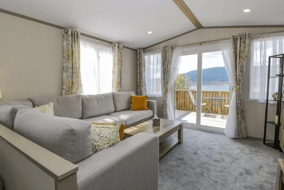 Living room at 11A Mansion View with sliding doors framing Loch Long from a grey corner sofa