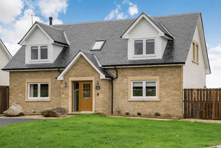 Fiadh Ruadh front exterior with sandstone walls, white render upper, slate roof and feature boulders