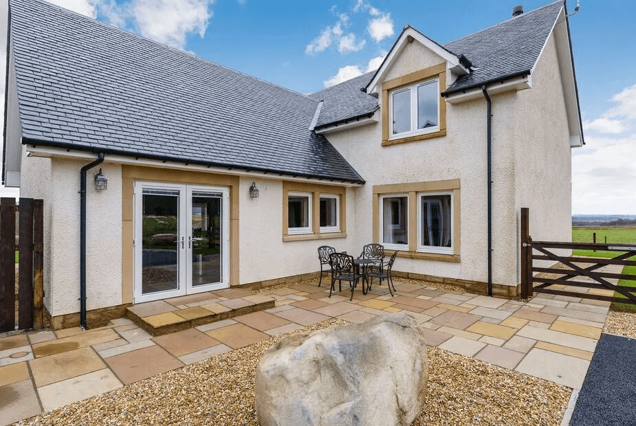 Gartclach rear patio with sandstone walls, French doors and outdoor furniture overlooking the field