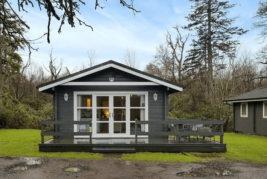 Leven Lodge 2 dark grey timber chalet with white French doors, gable roof and front deck