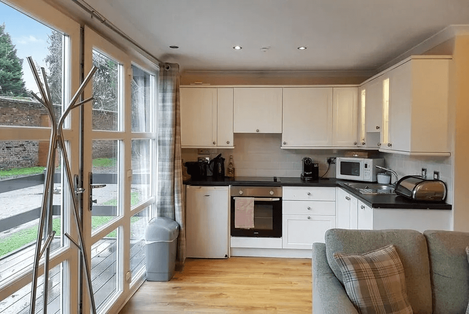 Galley kitchen at Leven Lodge 2 with white cabinetry and French doors out to the deck